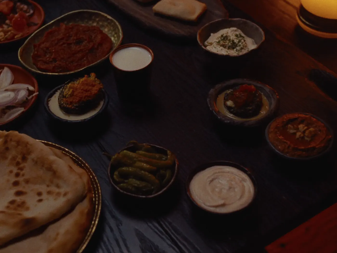 Mezze von oben: Ezme, Haydari, Muhammara mit Walnuss, Aubergine mit Tahin, eingelegte Peperoni, Fladenbrot und ein Kupferbecher Ayran.
